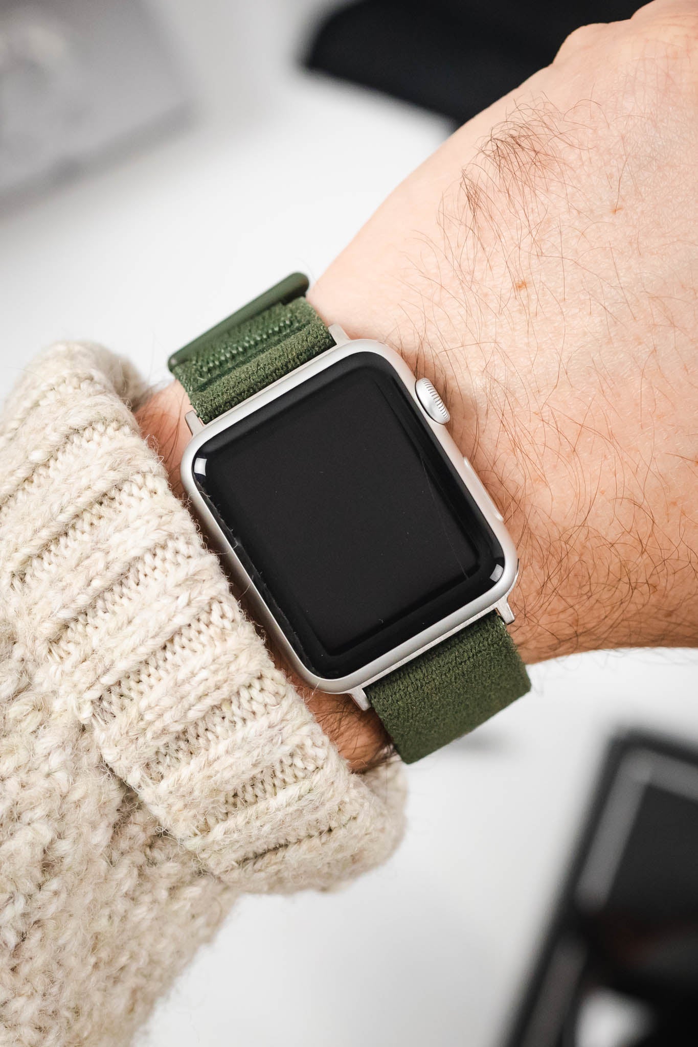Apple Watch on a durable HIRSCH Vocem Green textile strap, worn on a wrist over a chunky knit sweater.