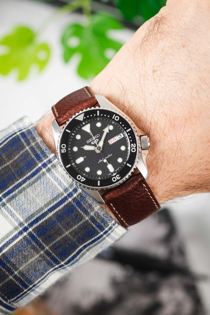 OMEGA x Swatch MoonSwatch Mission to the Moon on a black leather watch strap with white stitching, worn on a checkered shirt.