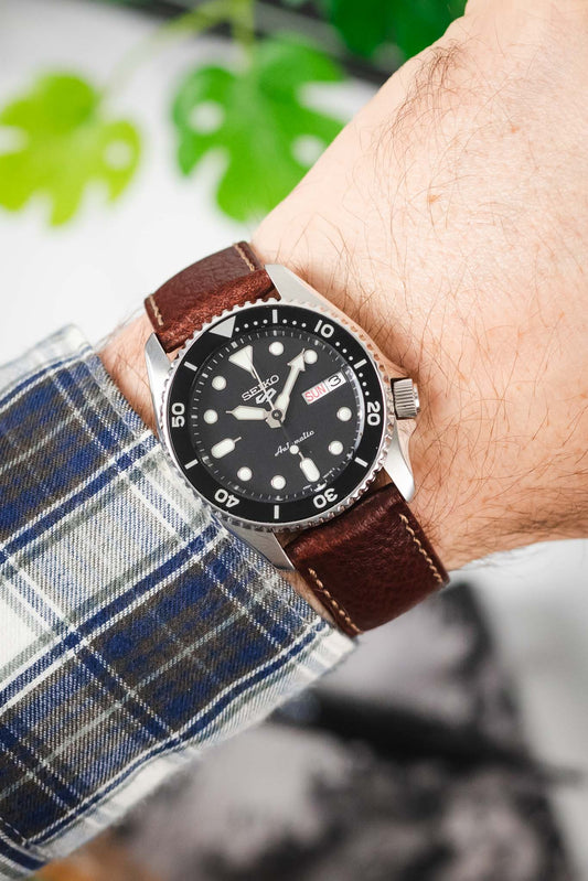 OMEGA x Swatch MoonSwatch Mission to the Moon on a black leather watch strap with white stitching, worn on a checkered shirt.