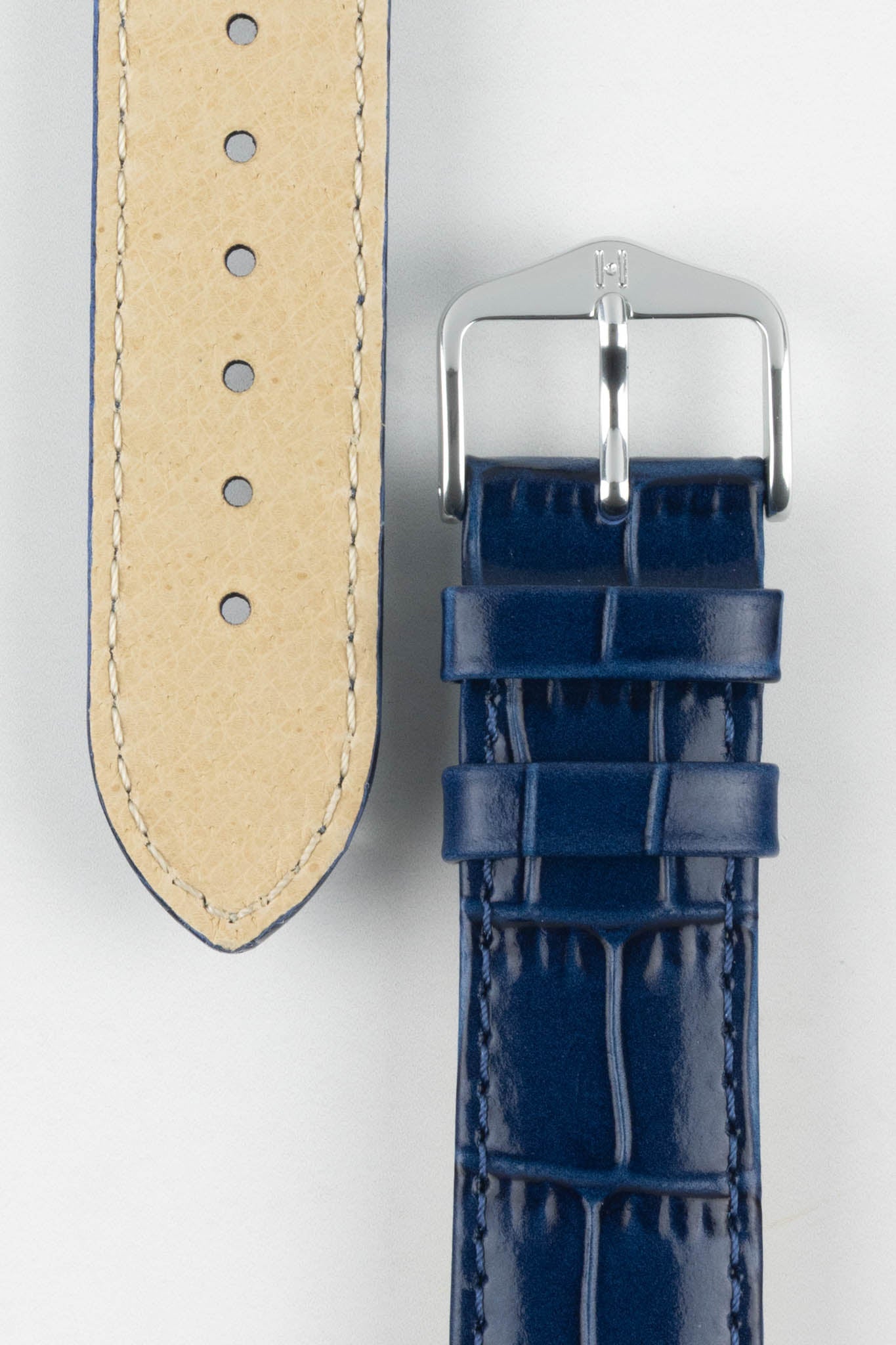 Close-up of the Louisianalook Blue embossed watch strap showing the tan lining and polished silver buckle.