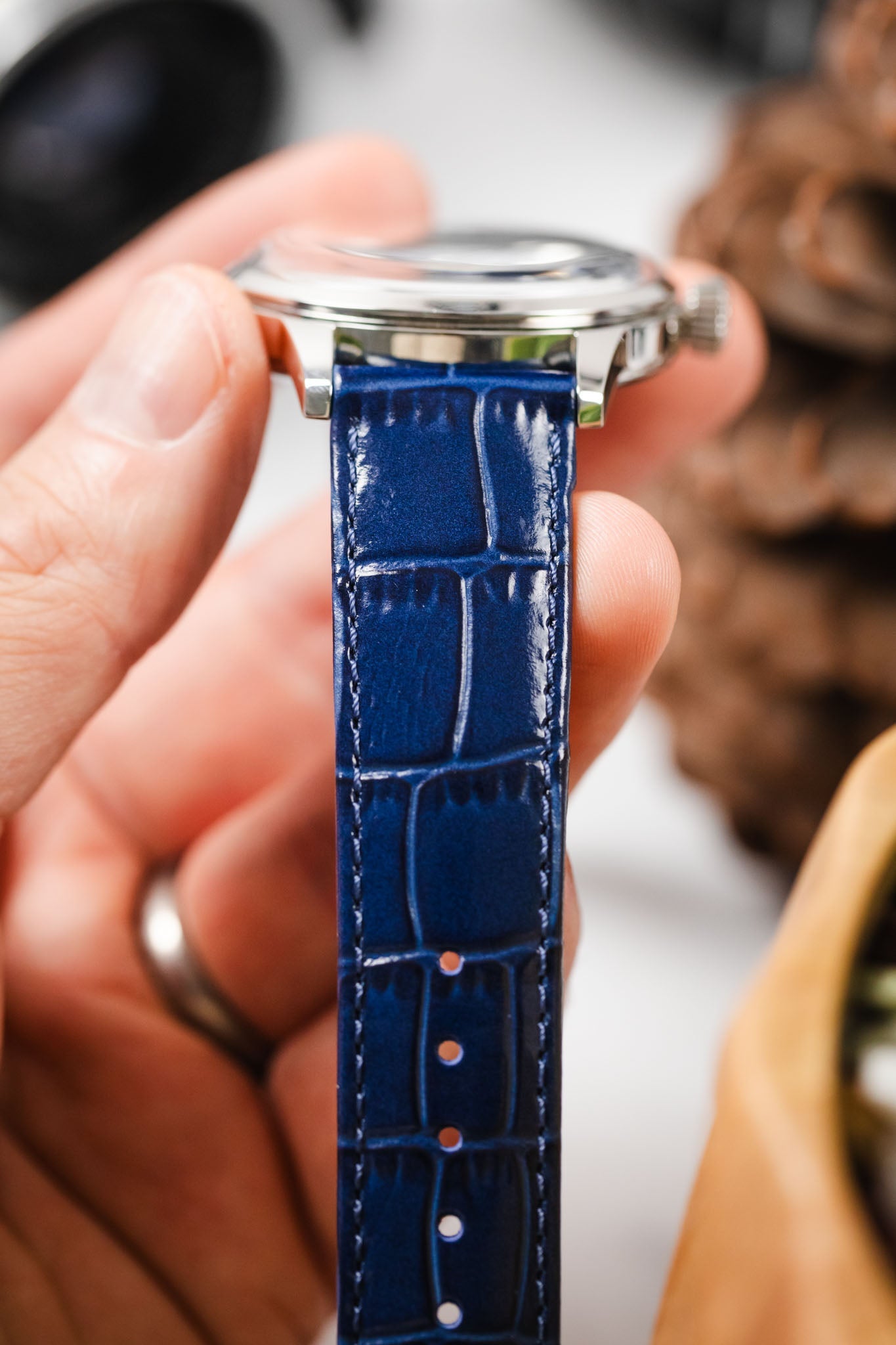 Hand holding a Seiko Presage watch with a close-up of the vibrant blue alligator-embossed watch strap.