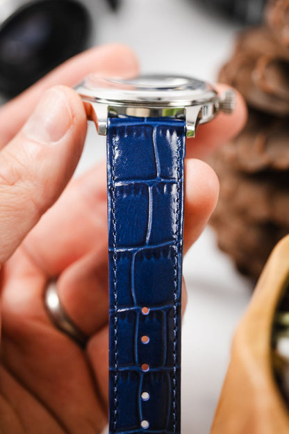 Hand holding a Seiko Presage watch with a close-up of the vibrant blue alligator-embossed watch strap.